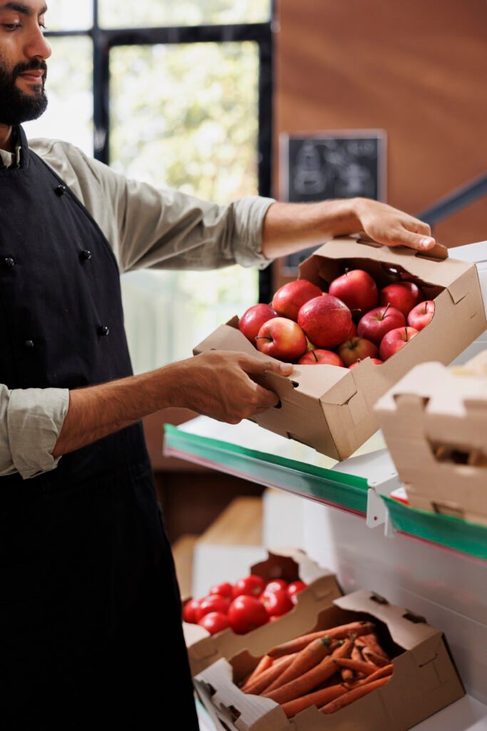 Comerciante que lleva una caja de manzanas en la tienda